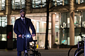 Portrait businessman with bicycle at night
