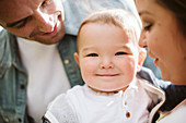 Parents holding cute baby boy looking at camera