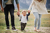 Parents walking with baby son in field