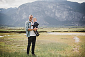 Father and baby son standing in rural field