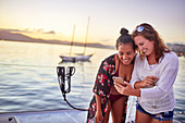 Young women friends using smart phone on boat