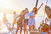 Playful women friends dancing on sunny catamaran