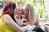Affectionate lesbian couple kissing daughter