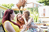 Lesbian couple holding daughter on sunny patio