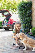 Girl giving treat to dog in driveway