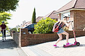 Girl riding scooter in sunny driveway