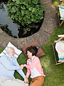 Senior couple laying by pond in garden