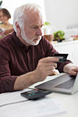 Senior man with credit card at laptop