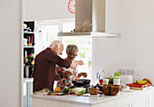 Active senior couple cooking in kitchen