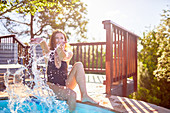 Young woman splashing water at swimming pool