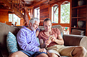 Father and son using smart phone on cabin sofa
