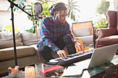 Young man recording music, playing keyboard