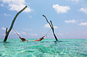 Woman laying in hammock over tranquil ocean