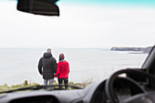 Couple looking at ocean view outside car