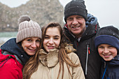 Snow falling over family posing in warm clothing