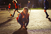 Portrait smiling girl soccer player tying shoe