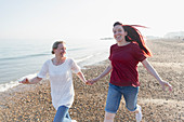 Playful lesbian couple running on beach