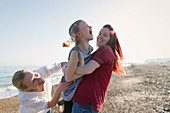 Lesbian couple and daughter laughing on beach