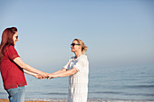 Lesbian couple holding hands on ocean beach