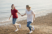 Playful lesbian couple holding hands and running