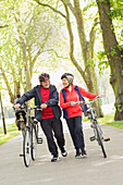 Active senior couple walking bicycles in park
