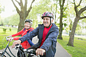 Active senior couple riding bikes in park