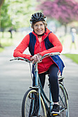 Portrait active senior woman riding bike in park