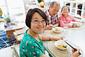 Portrait woman eating noodles with family at table