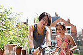 Mother and daughter gardening in yard