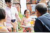 Granddaughter serving orange juice to grandfather