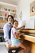 Portrait mother and daughter playing piano