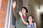 Mother and daughter waving at front door