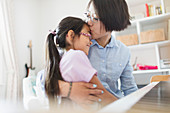 Mother and daughter hugging, playing piano