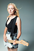 Portrait cool young woman playing electric guitar