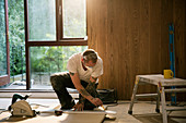 Construction worker measuring wood board in house