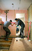 Construction workers using level tool in house