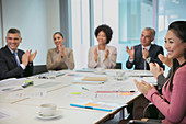 Smiling business people clapping in meeting