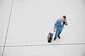 Businessman with suitcase talking on cell phone
