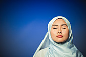 Serene young woman wearing blue silk hijab