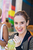 Portrait happy young woman drinking green smoothie