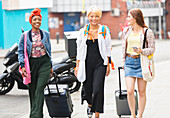 Smiling women friends with suitcases walking