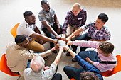 Men joining fists in circle in group therapy