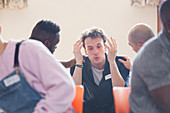 Men comforting man talking in group therapy