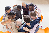Men hugging in huddle in group therapy