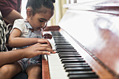 Curious toddler girl playing piano