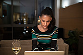 Woman drinking white wine and working at night