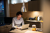 Man drinking white wine at laptop at night