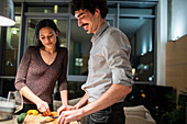 Couple cutting vegetables, cooking dinner