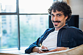 Portrait smiling man using smart phone on sofa