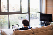 Man using laptop on apartment sofa